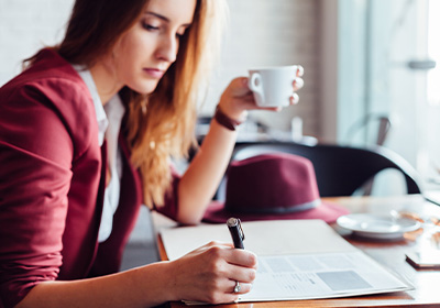 Woman writing while drinking coffee